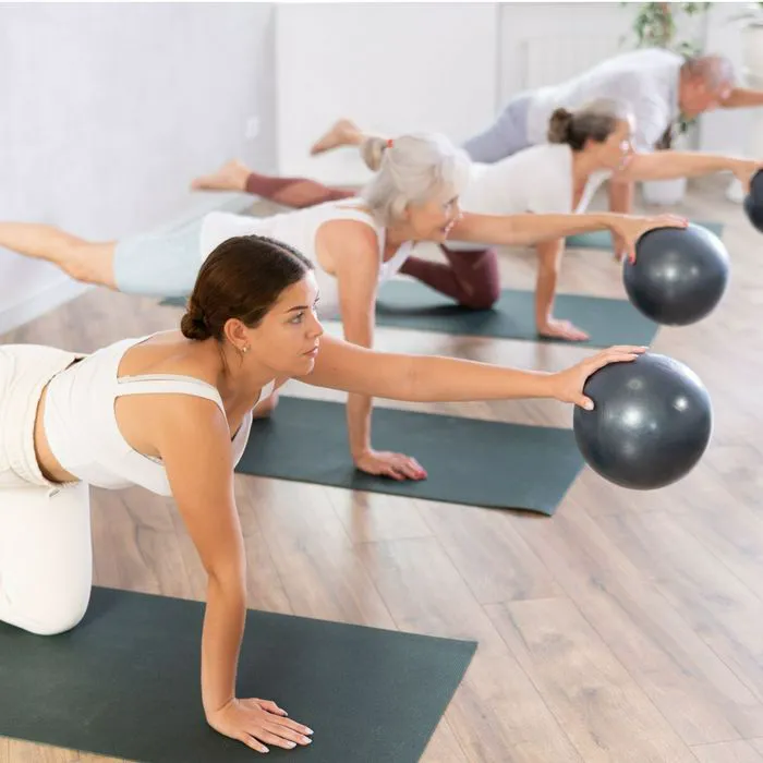 group of women doing bird dog pose with ball