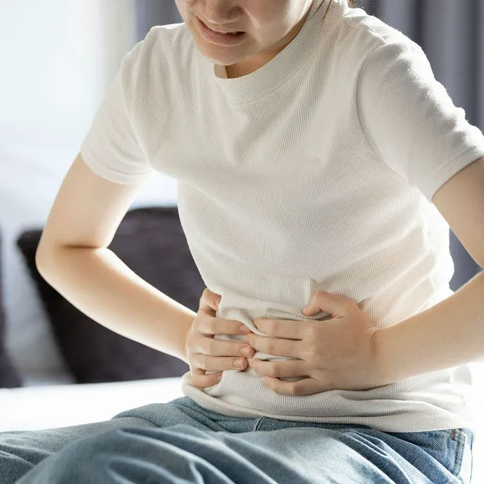 "Woman experiencing bloating and stomach pain in bed"