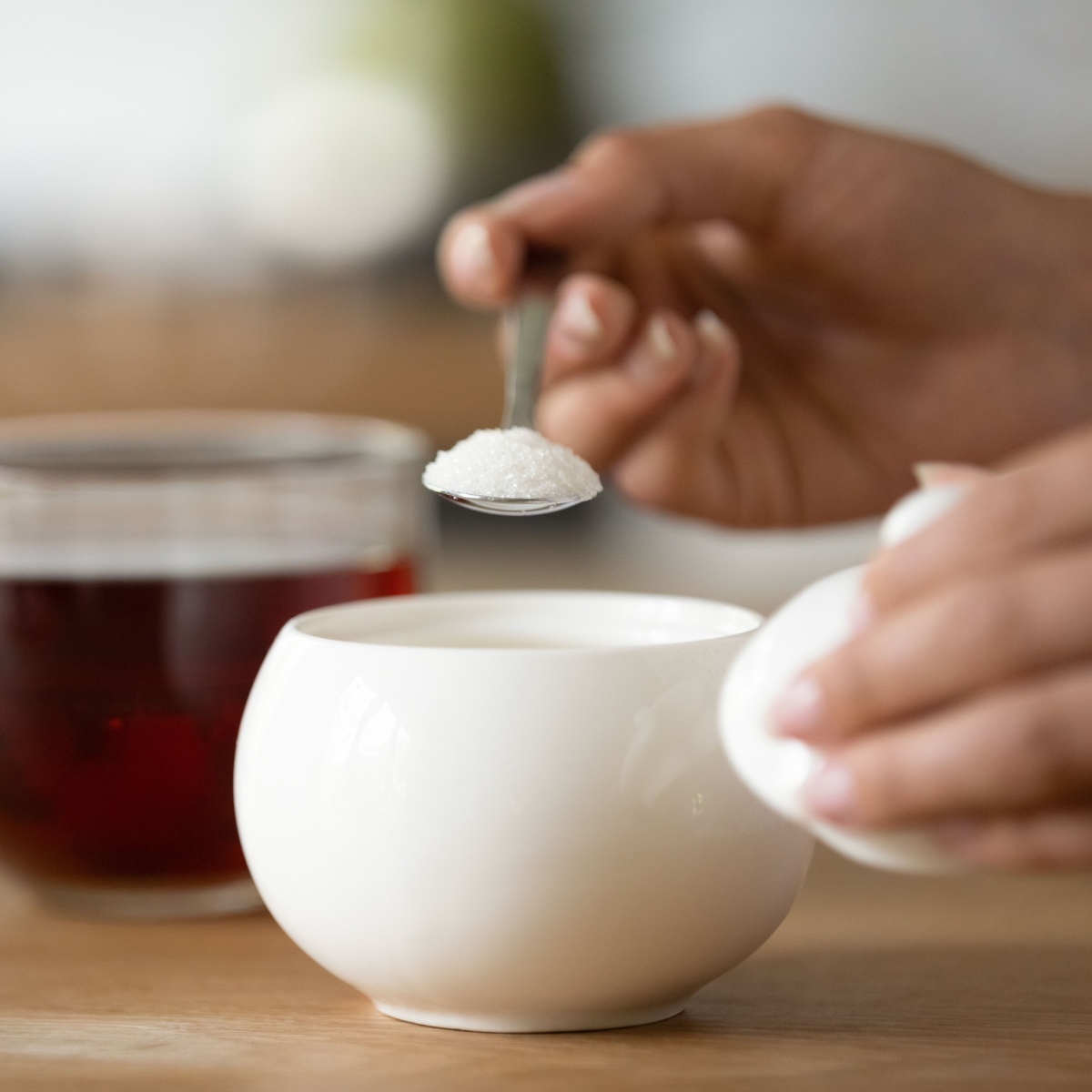 person pouring sugar in tea