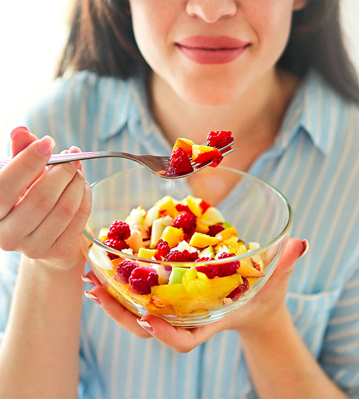 woman eating bowl of fruit salad