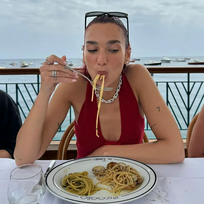 Dua Lipa eating pasta in red halter top