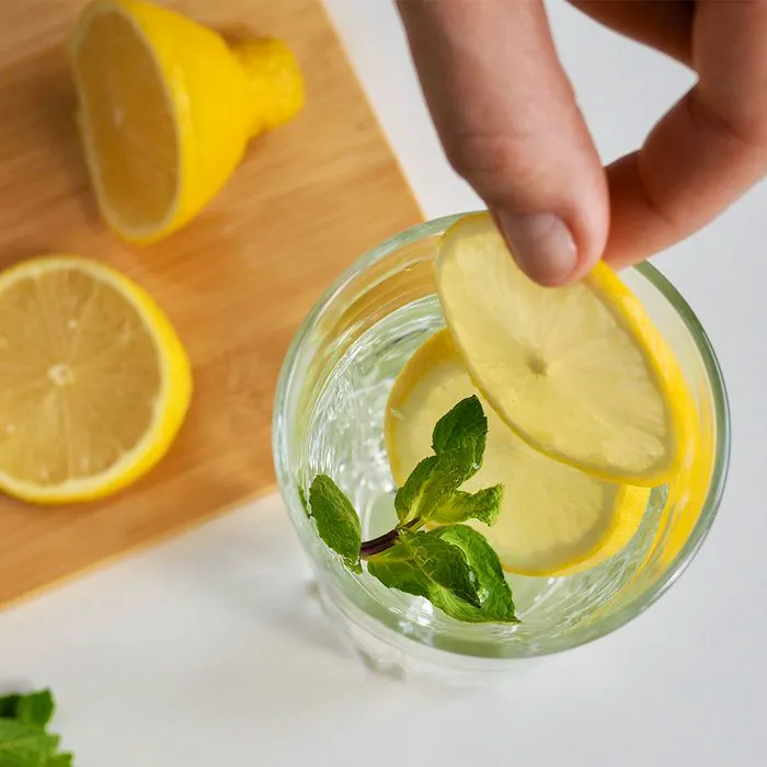 Preparing refreshing lemon water beverage with fresh lemons.