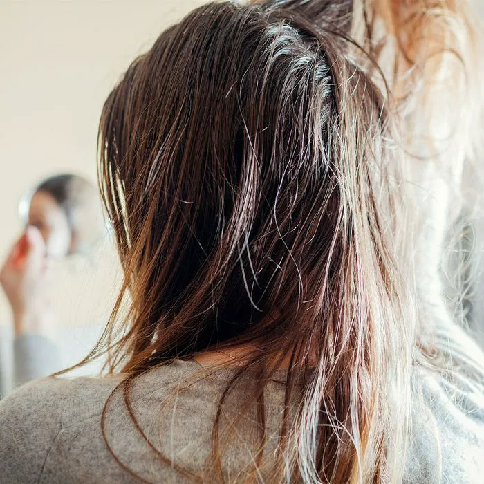 "Woman assessing her messy oily hair"