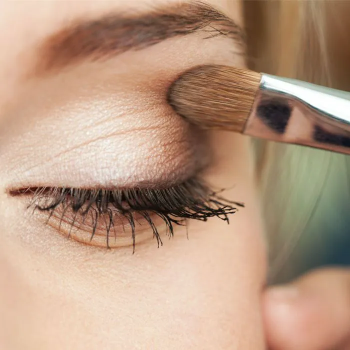 Applying smokey glittery eyeshadow with a metal brush.