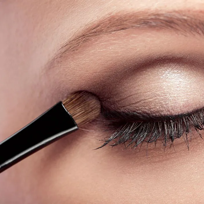 Close-up of a woman applying shimmer eyeshadow.