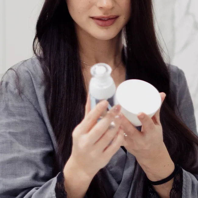 Holding various skincare products for healthy skin.