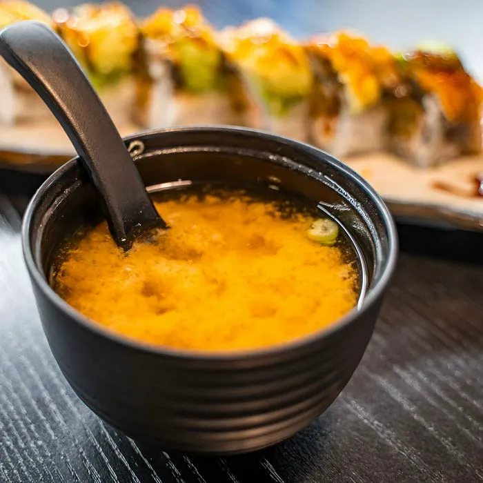Japanese restaurant meal with miso soup and sushi roll.