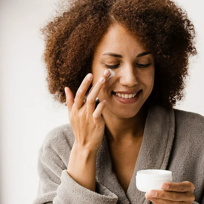 Woman applying moisturizer while wearing a bathrobe.