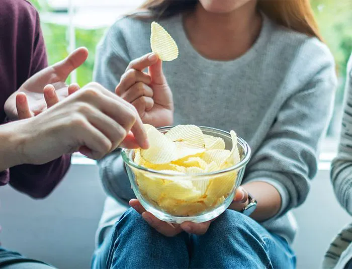 Friends enjoying a bowl of potato chips together.