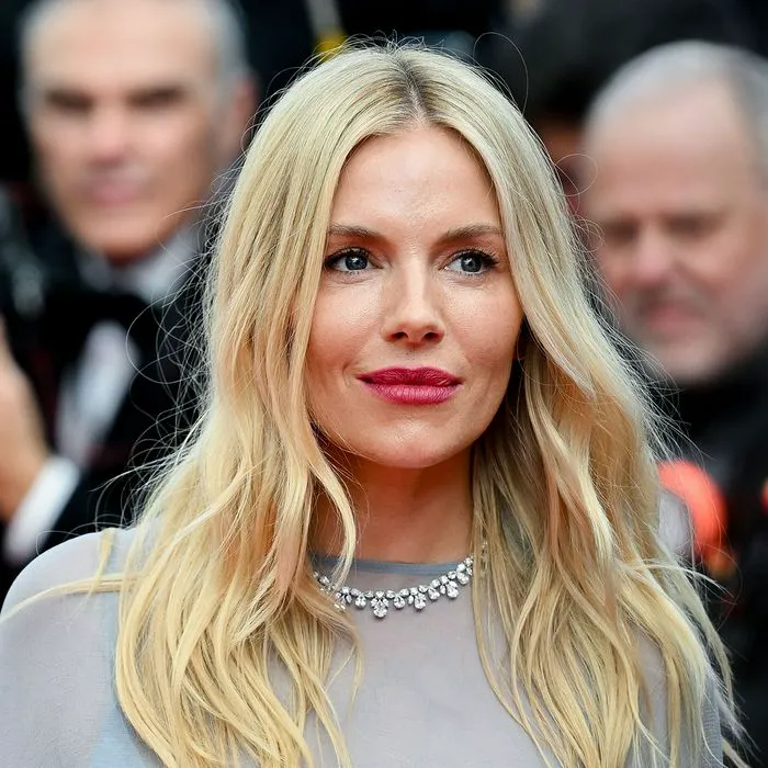 Sienna Miller in a stylish tan pantsuit at red carpet event.