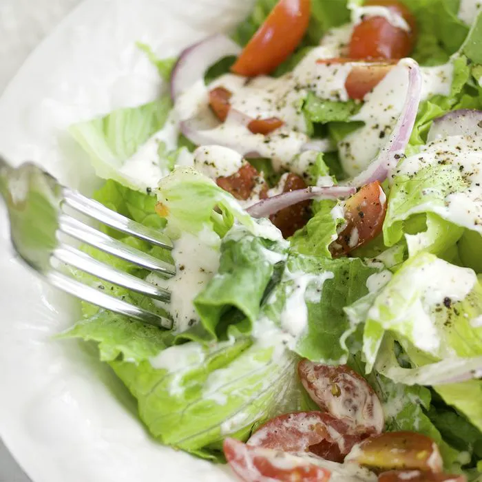 Close-up of fresh salad drizzled with ranch dressing