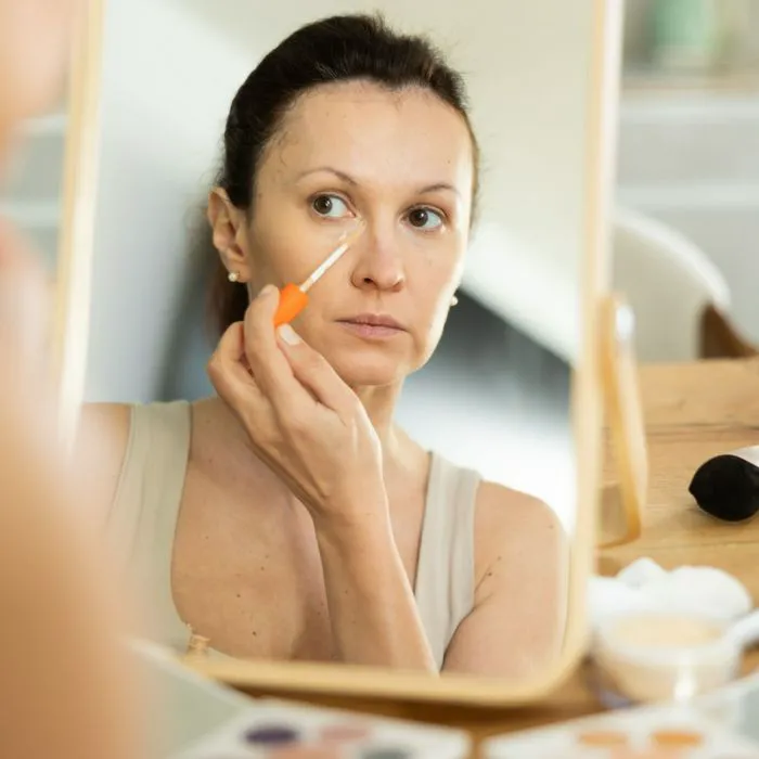 "A woman smiling while applying foundation"
