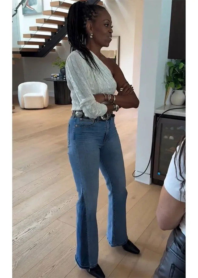 Michelle Obama in stylish one-shoulder sweater and flare jeans.
