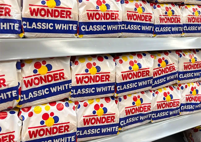 Freshly sliced classic white wonder bread on a wooden board.