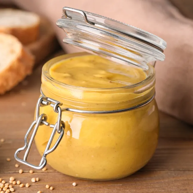 Jar of honey mustard sauce on a table.