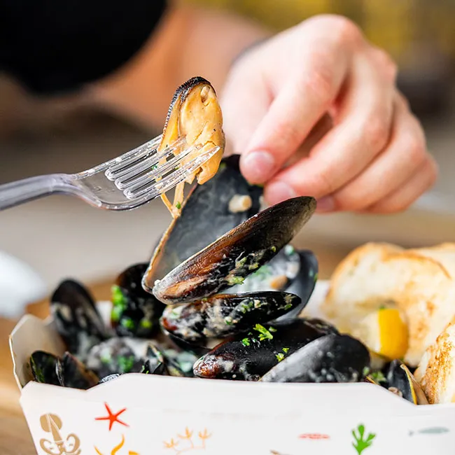 Person enjoying mussels with bread for anti-aging benefits.