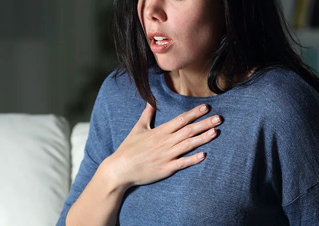 Woman experiencing chest pain, looking worried and distressed.
