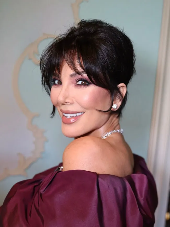 Kris Jenner elegantly posing in her purple DG gown.