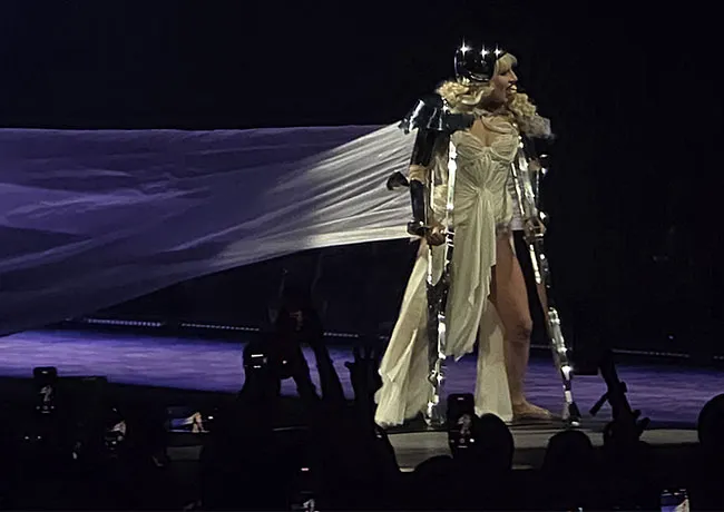 "Lady Gaga using crutches in a white corset dress"