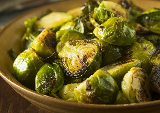 Bowl of roasted Brussels sprouts garnished and ready to serve.