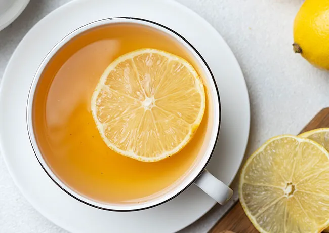 Refreshing cup of tea with lemon slice on the rim.