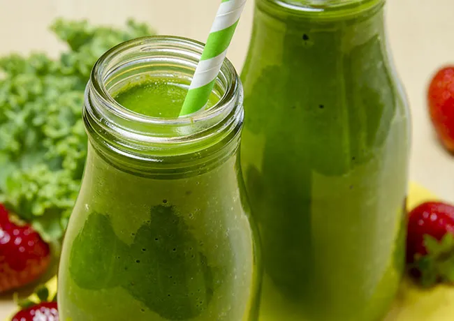 Bottles of green juice lined up on a shelf