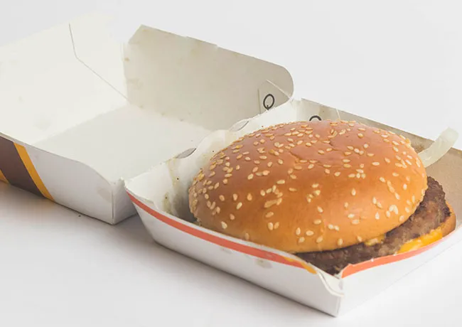 Unappetizing McDonald's burger inside its takeout box.