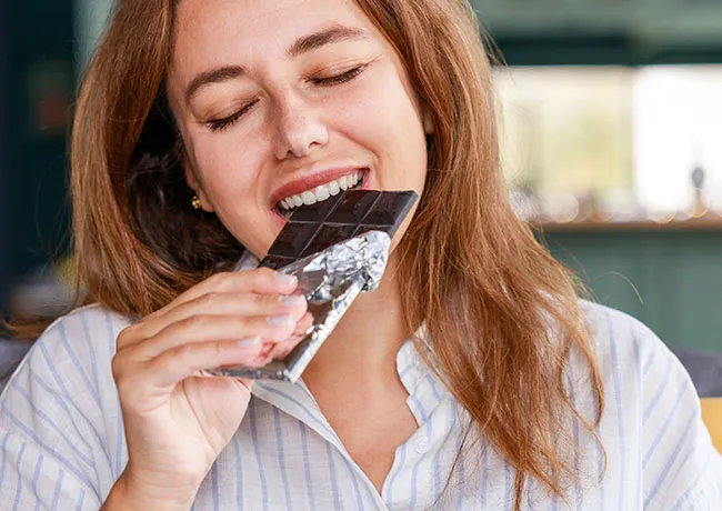 Woman enjoying a bite of dark chocolate bar