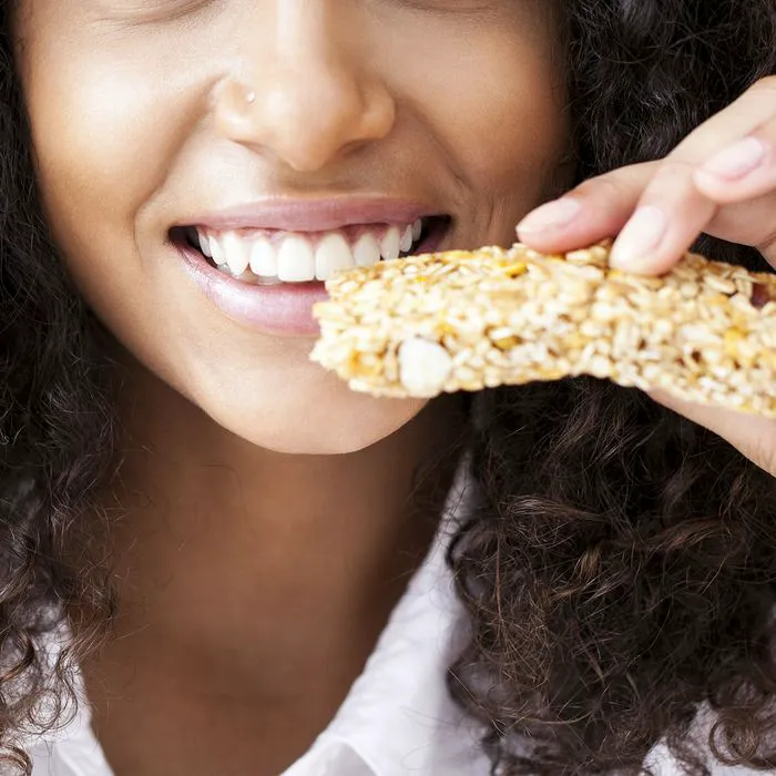 woman biting into granola bar