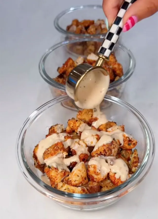 Pouring savory garlic parmesan sauce over a dish.