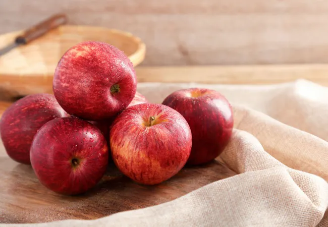 Vibrant bowl of Gala apples with green leaves