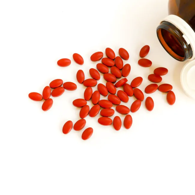 Iron pills spilling out of a supplement bottle