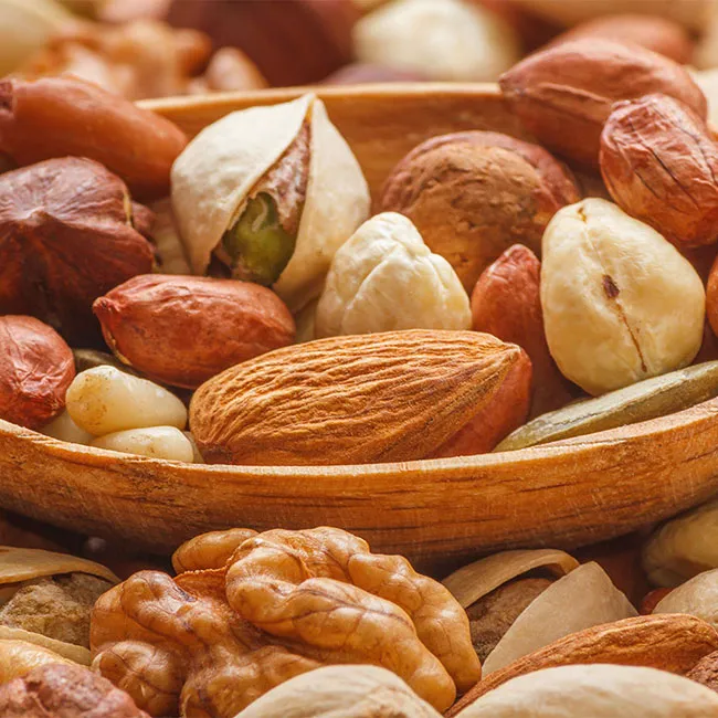 Assorted mixed nuts and seeds in a decorative bowl.