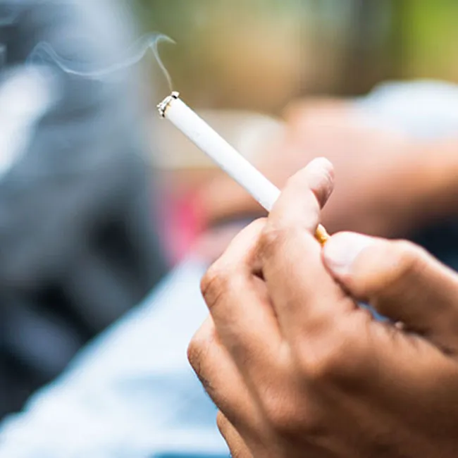 Person holding a cigarette, illustrating smoking habits.