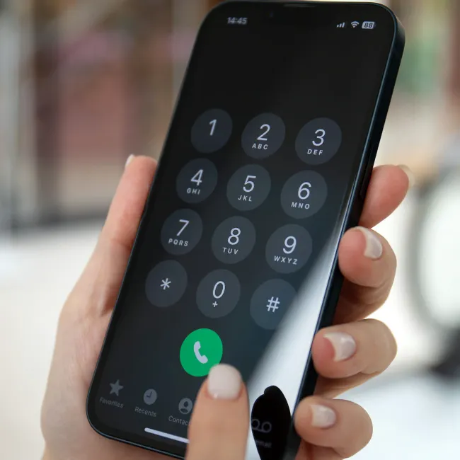 Person dialing a number on an iPhone.