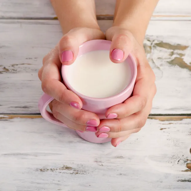 Warm mug of milk held in hands.