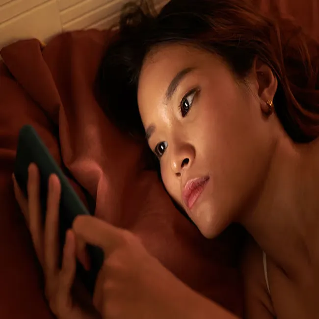 Woman looking at her phone in bed at night.