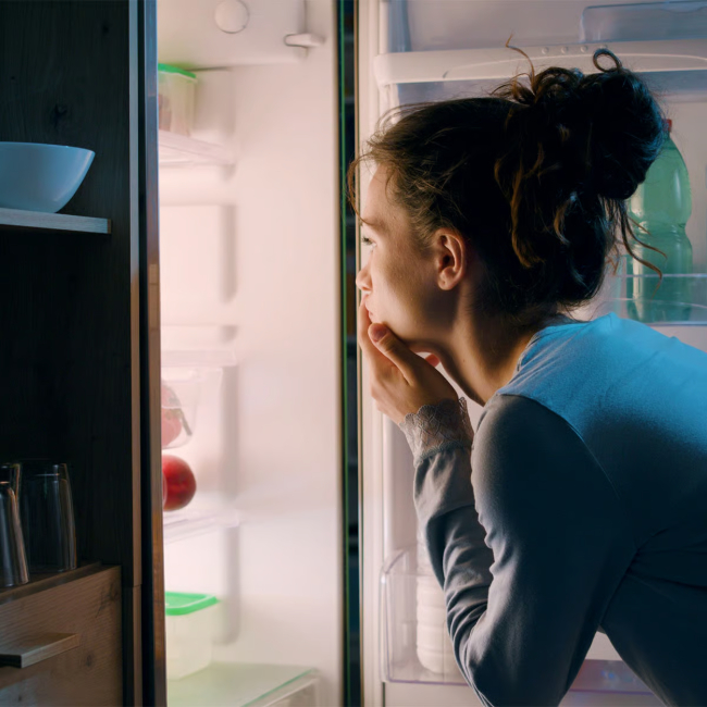 Woman searching for a late-night snack in the fridge.