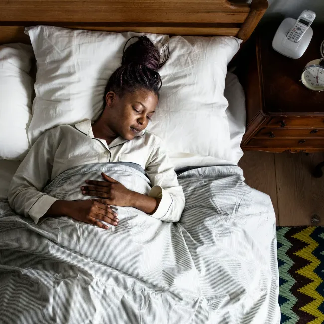 Woman sleeping soundly in bed, peaceful expression.
