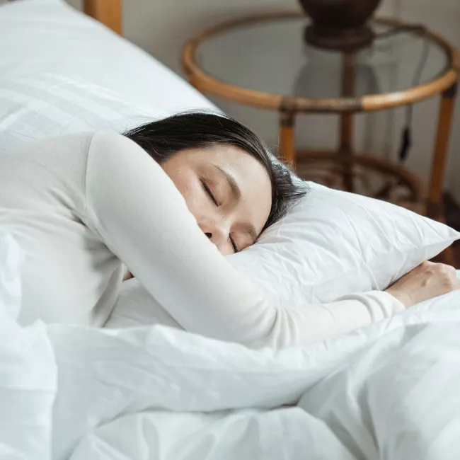 Woman peacefully sleeping in bed during the morning light.