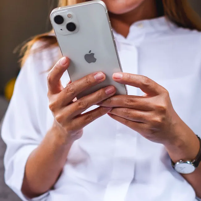 Woman using iPhone 13 smartphone for style and beauty tips.
