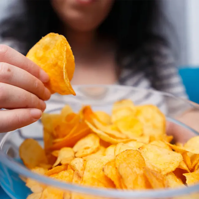 Close-up of a woman enjoying a bowl of chips.