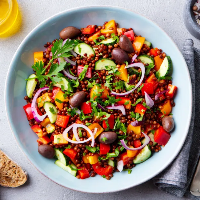 Lentil bowl topped with fresh herbs and vegetables.