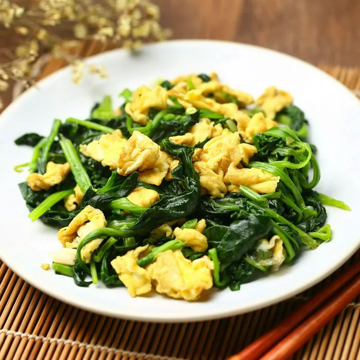 Creamy scrambled eggs with fresh spinach garnish.
