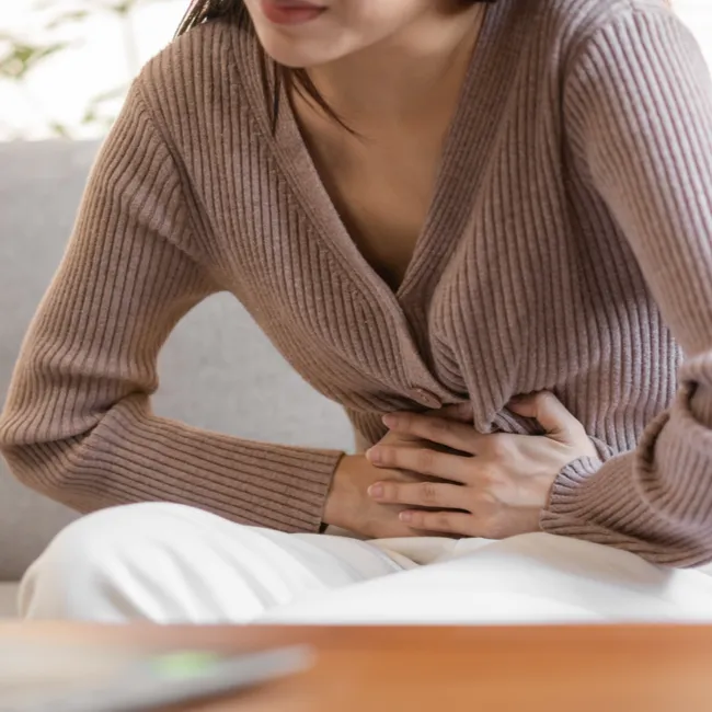 Woman holding her stomach, reflecting on motherhood and support.