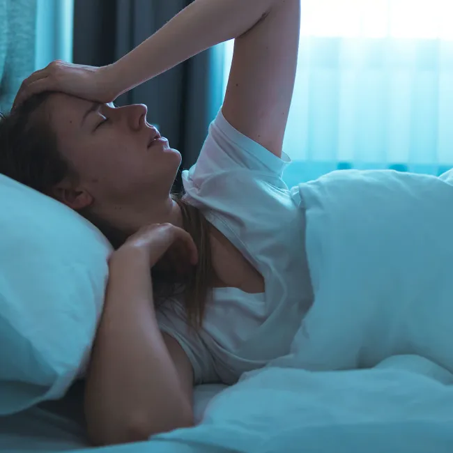Young woman struggling with restless sleep in bed