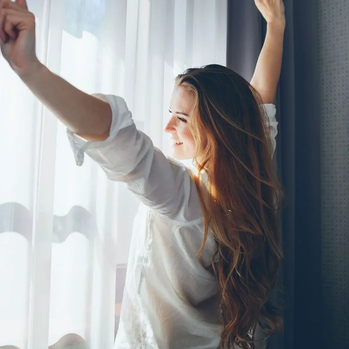"Woman waking up with sunshine stretching"