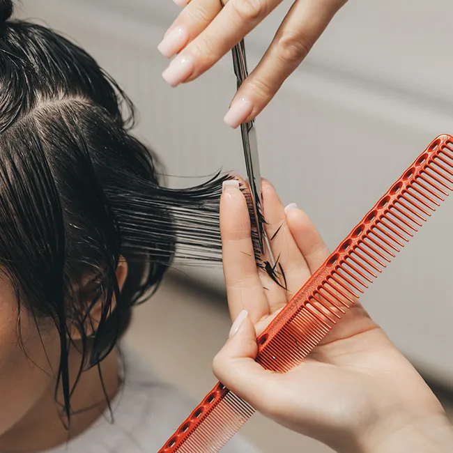Woman receiving a haircut at a busy salon.