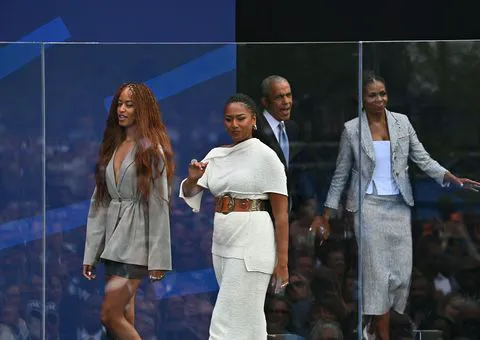 Sasha and Malia Obama with Barack and Michelle Obama at a ceremony.