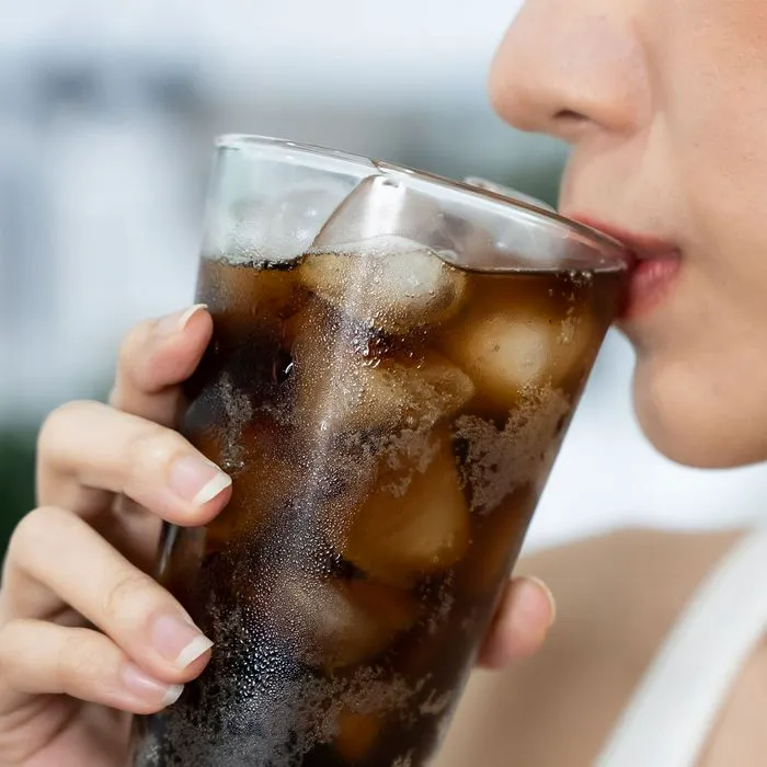 Woman enjoying a refreshing glass of soda outdoors.